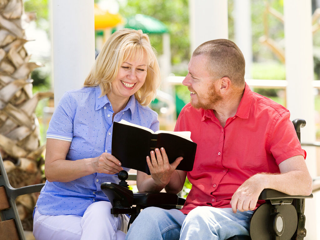 man in wheelchair reading with wife